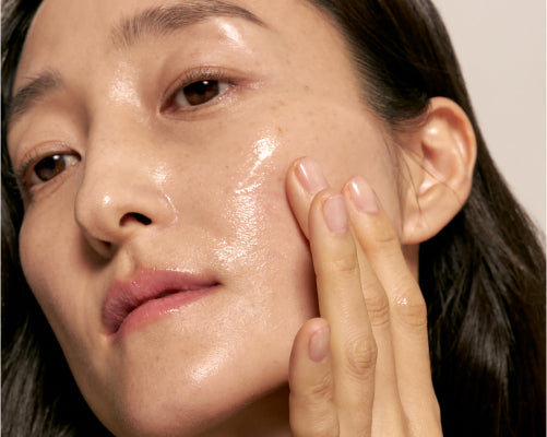 Applying RED RICE HYDRATING SERUM to face by woman