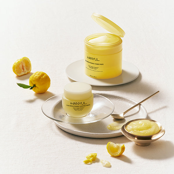 Display of HANYUL Yuja Brightening Sleeping Mask and Toner Pads with fresh yuja fruits.
